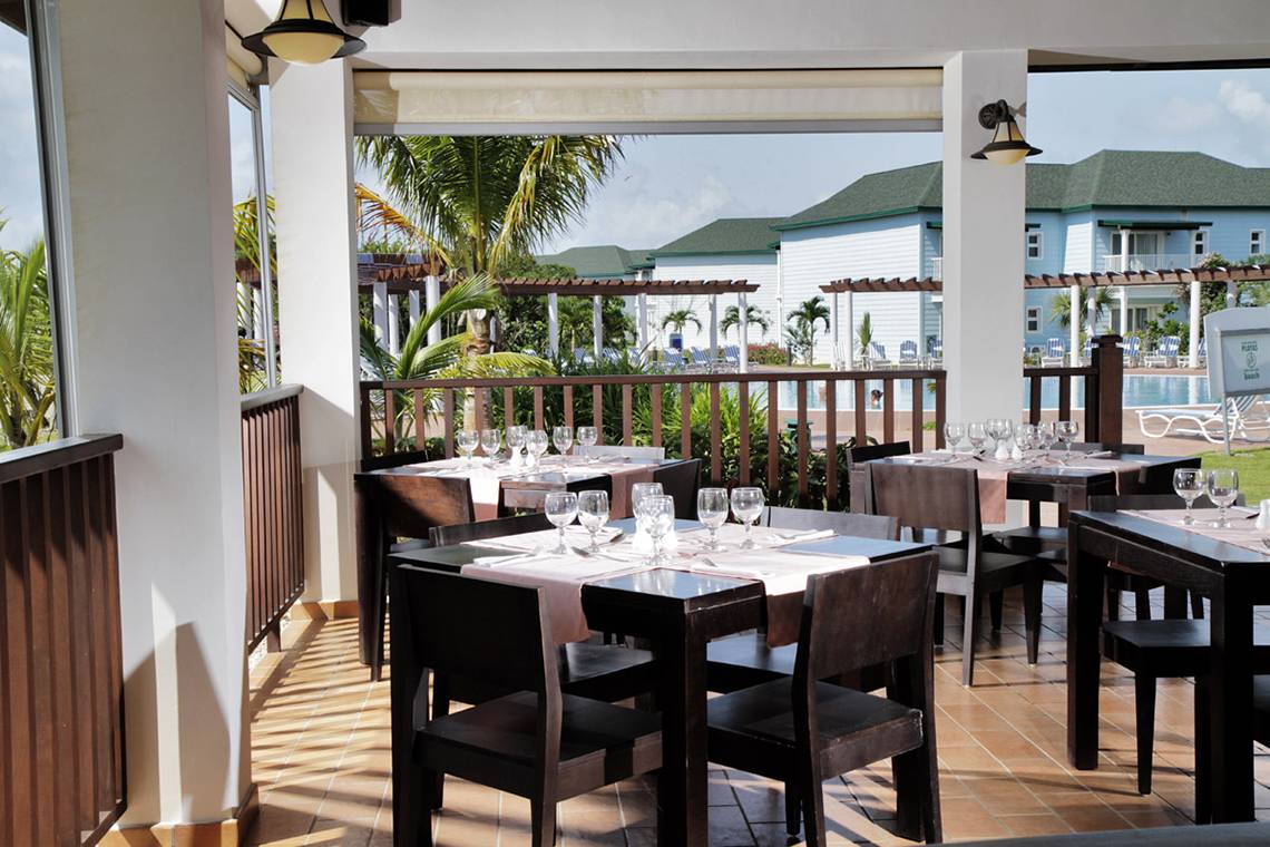 Terrasse des Valentin Varadero El Patriarca Hotels mit Tischen und Stühlen und Blick auf das Meer.