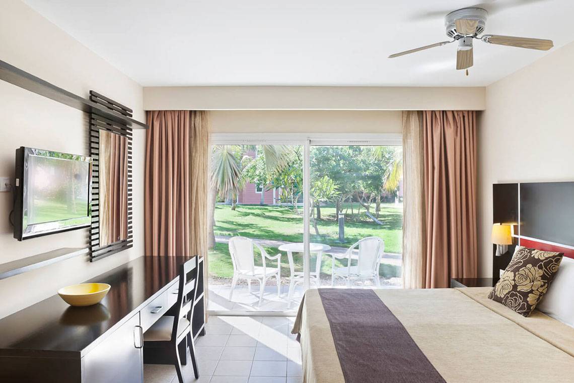 Hotelzimmer mit Schlafzimmer, Schreibtisch, Fernseher, Terrasse und Gartenblick.