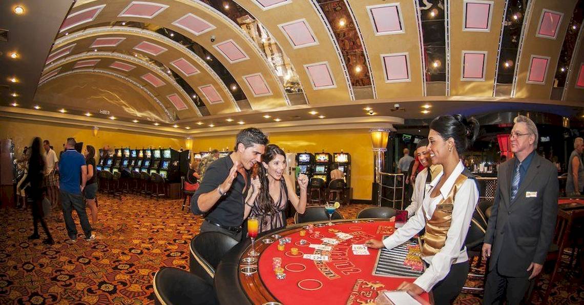 Casino mit Spielen und Spielern, darunter ein Mann und eine Frau, die am Tisch sitzen und spielen.