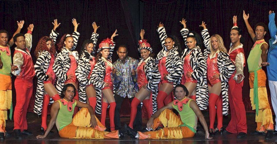 Eine Gruppe von Tänzern und Tänzerinnen in bunten Kostümen, die eine Show auf der Bühne des Grand Palladium Bavaro Suites Resort & Spa veranstalten.