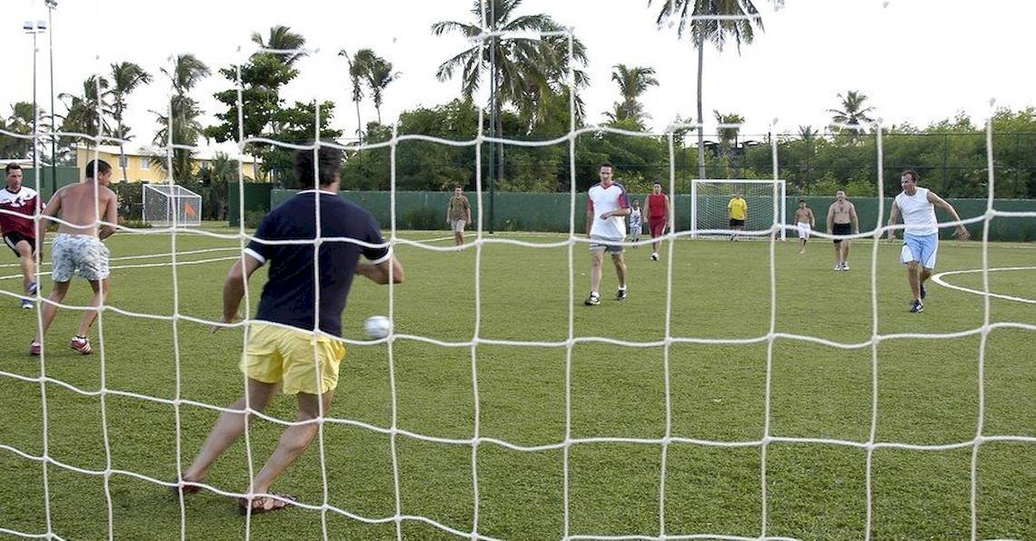 Gruppe von Männern spielt Fußball auf einem gepflegten Rasenfeld im Freien, Grand Palladium Bavaro Suites Resort & Spa