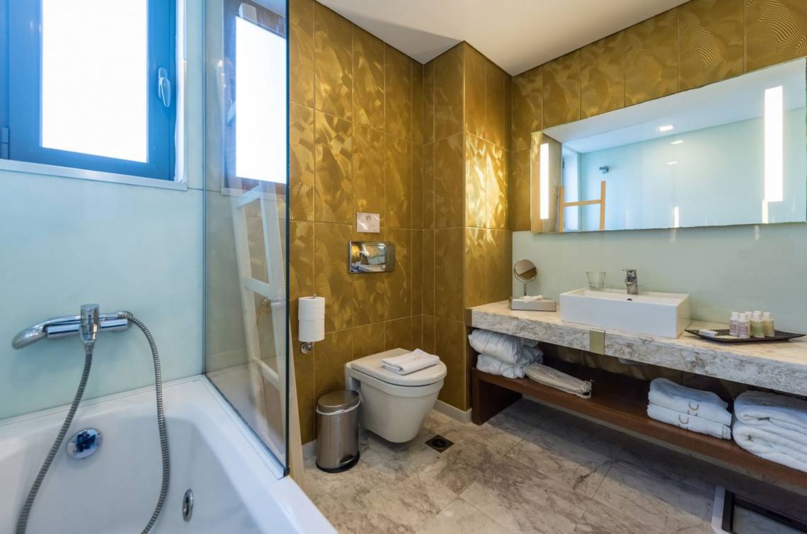 Badezimmer im Diamond Deluxe Hotel mit goldenen Wänden, Badewanne, Toilette und Waschbecken.