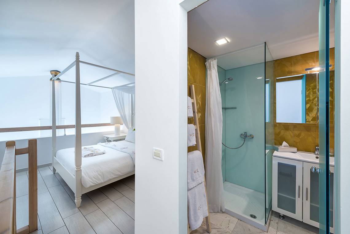 Schlafzimmer und Badezimmer im Diamond Deluxe Hotel mit vierposterbett und blauer Duschkabine.