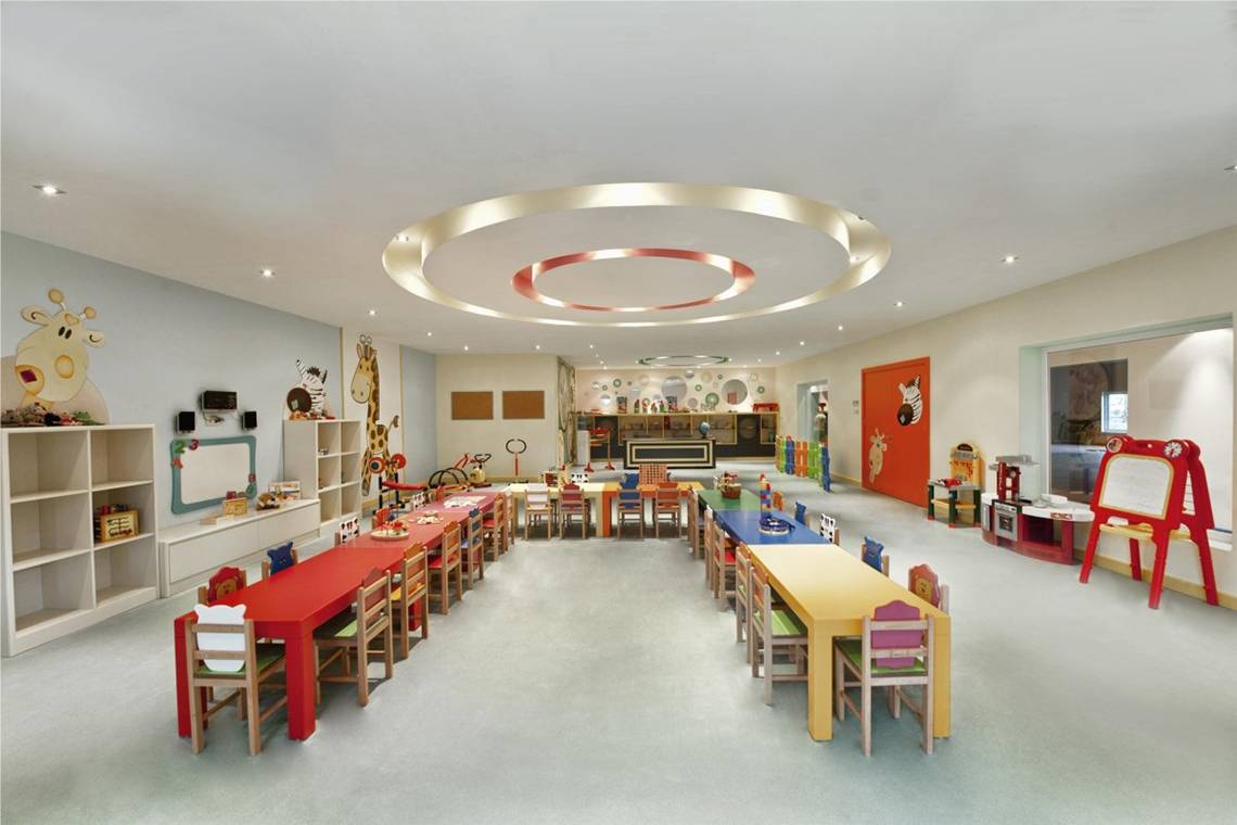 Ein kinderzimmer im Maxx Royal Belek Golf Resort mit bunten tischen und stühlen.