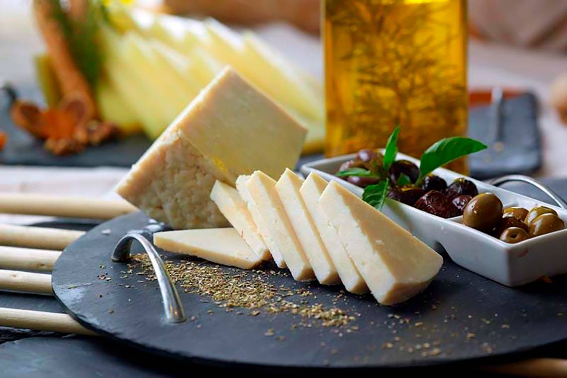 Gewürzter Käse auf einer schwarzen Schale mit Oliven und Gewürzen