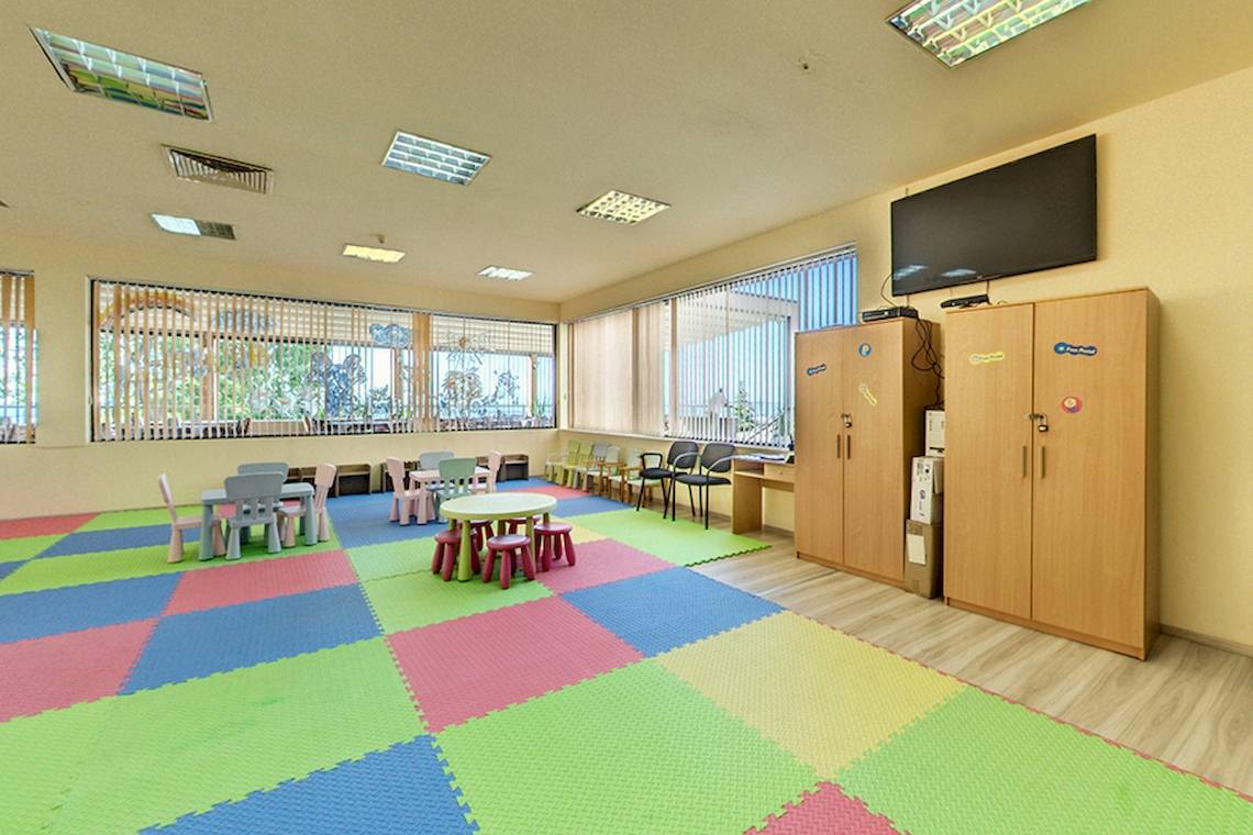 Das Kinderzimmer im Bellevue Hotel mit bunten Teppichfliesen und Spieltischen.