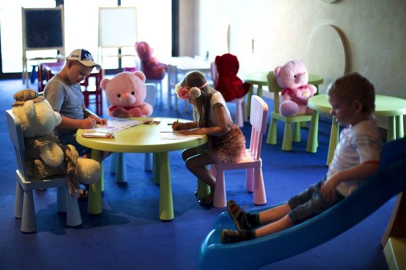 Kinder im Spielzimmer des Marjan Island Resort & Spa, das mit weichen Teppichböden und bunten Möbeln ausgestattet ist.