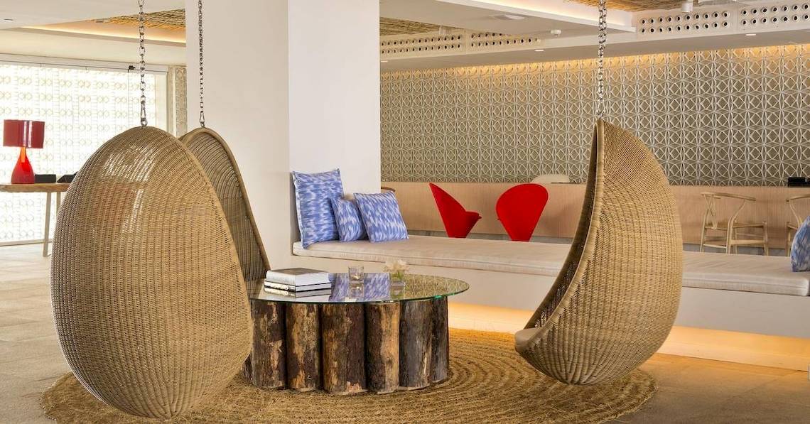 Loungebereich des ME Ibiza Hotels mit zwei Hängesesseln und einem Tisch.