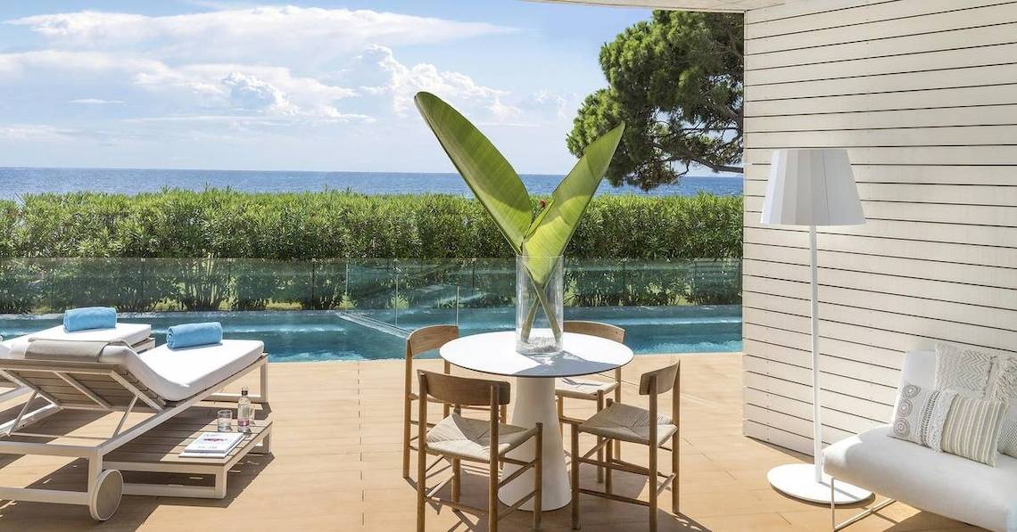 Terrasse des ME Ibiza Hotels mit Blick auf das Meer und eine begrünte Landschaft.
