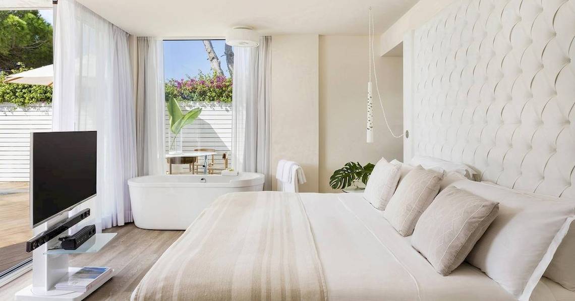Schlafzimmer im ME Ibiza Hotel mit Badewanne, Fernseher und Pflanzen.