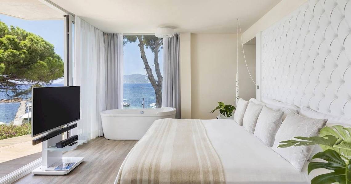 Schlafzimmer des ME Ibiza Hotels mit Blick auf das Meer und einen Baum.