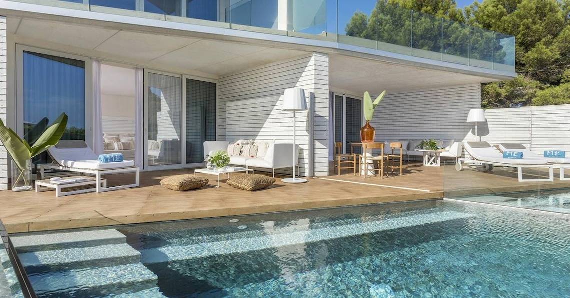 Außenbereich des ME Ibiza Hotels mit Swimmingpool, Loungemöbeln und Glaswänden