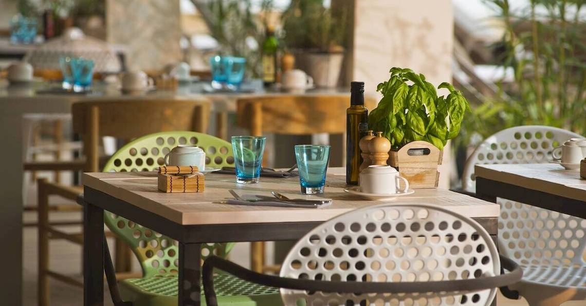 Restauranttisch im ME Ibiza Hotel mit grünen Stühlen und Holztisch.