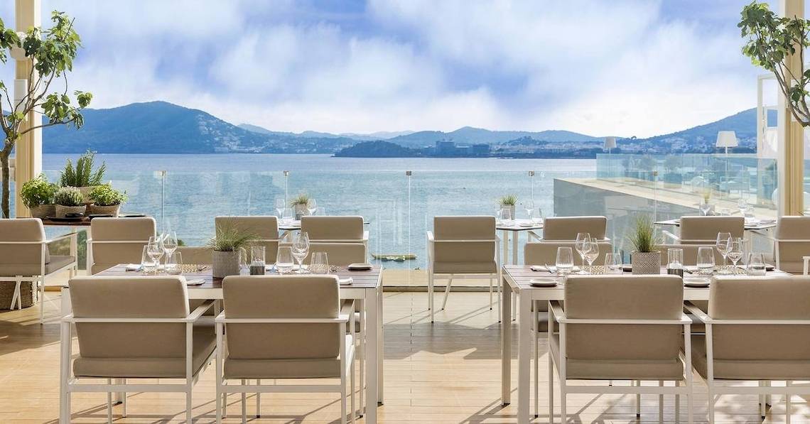Terrasse des ME Ibiza Hotels mit Blick auf das Meer und Berge
