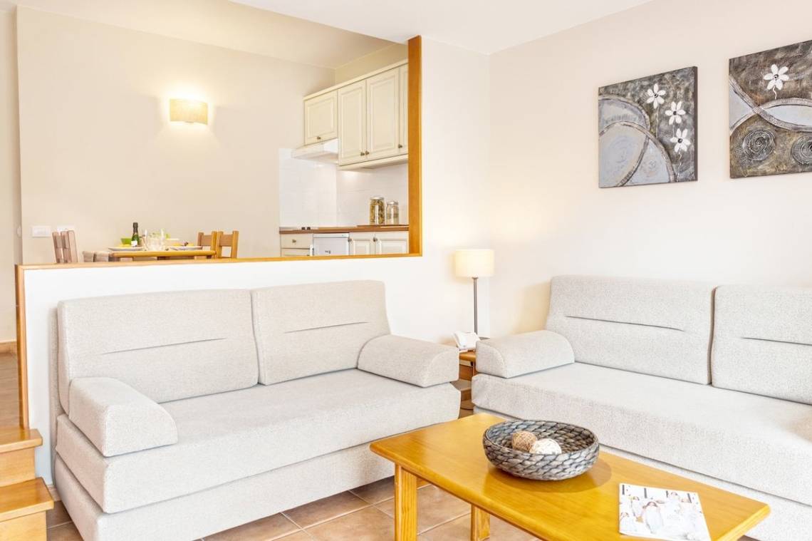 Wohnzimmer mit zwei weißen Sofas und einem Tisch mit einer Zeitschrift darauf.