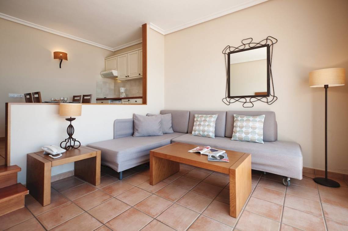Wohnzimmer mit Sofa, Tisch, Lampen und Spiegel im Sotavento Beach Club
