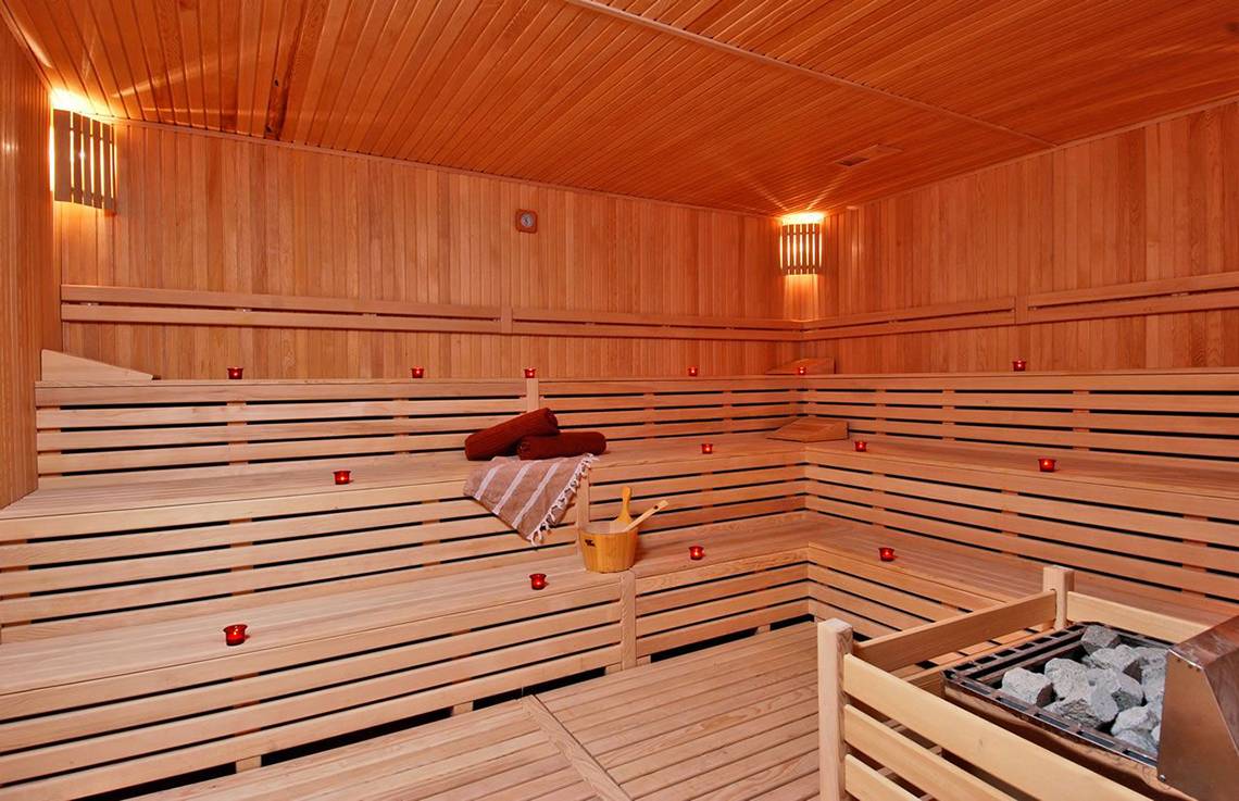 Innenansicht der Sauna im Botanik Platinum Hotel mit Holzbänken, Kerzen und Handtuch.