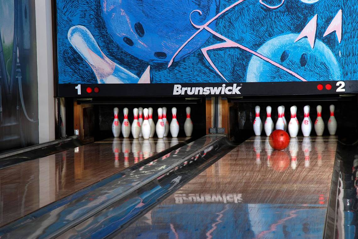 Eine Bowlingbahn mit einer roten Bowlingkugel und einer Zieltafel im Hintergrund.