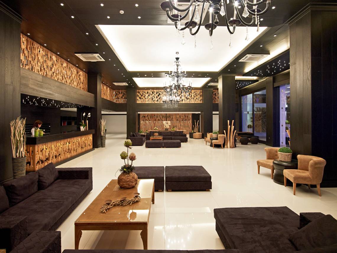 Lobby des Mitsis Faliraki Beach Hotel & Spa mit modernem Design, dunklen Möbeln und weißen Böden.