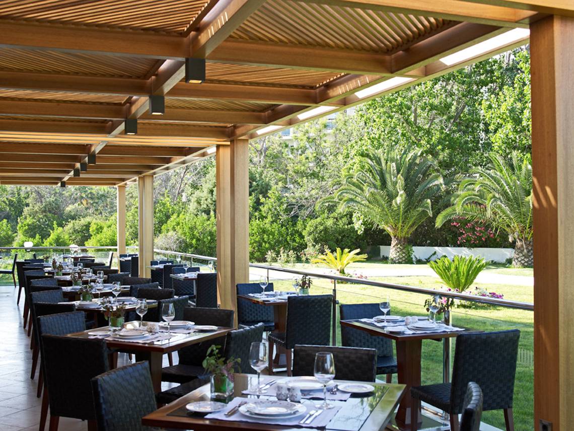 Außenbereich des Mitsis Faliraki Beach Hotel & Spa Restaurants mit Tischen und Stühlen unter einem Dach.