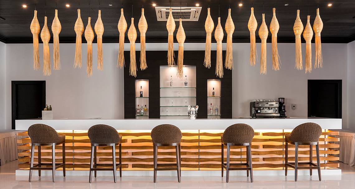 Barbereich des Mitsis Faliraki Beach Hotel & Spa mit modernen Stühlen und goldfarbenen Beleuchtungselementen