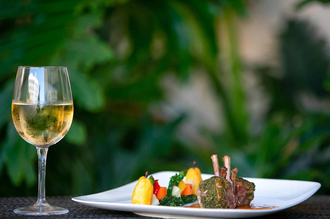 Ein Glas mit weißem Wein neben einem Gericht im Golden Bay Beach Hotel.
