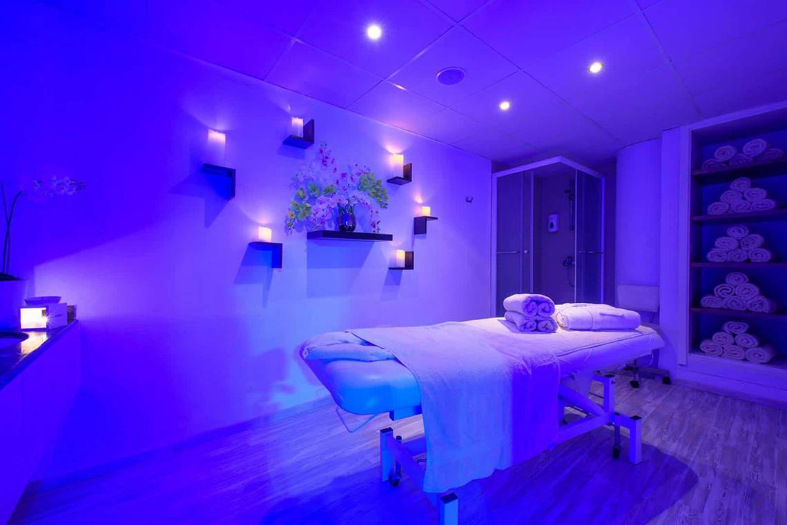 Behandlungsraum im Golden Bay Beach Hotel mit violettem Licht und Massagetisch