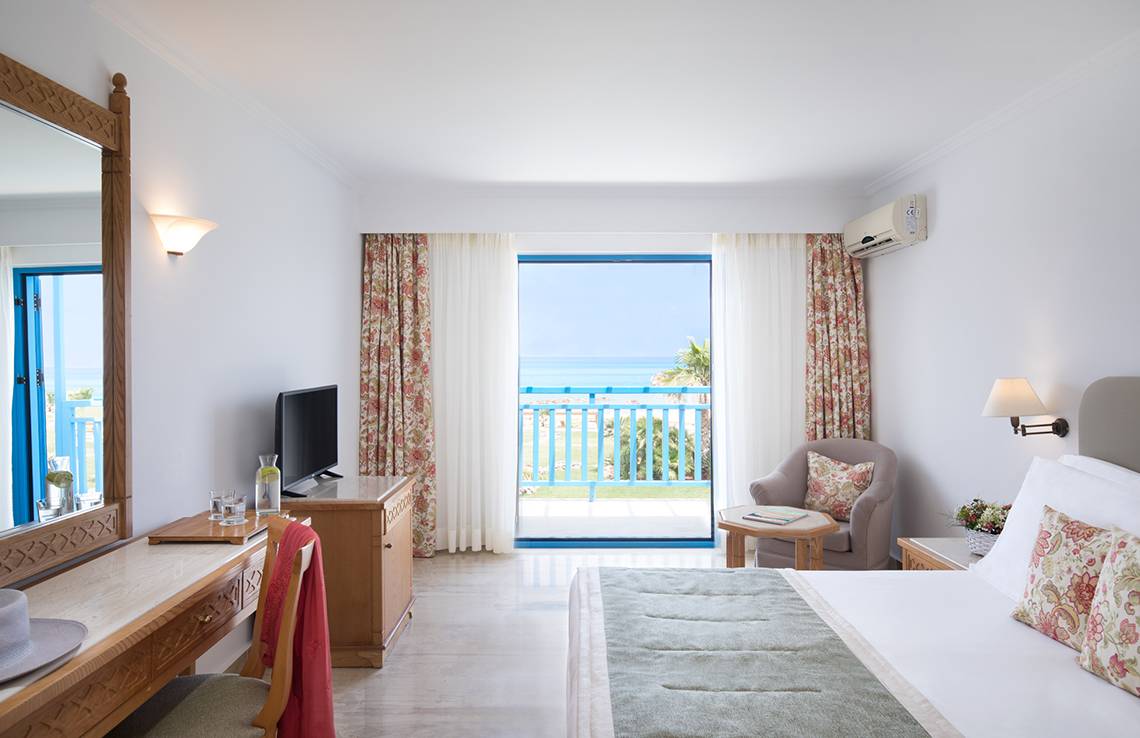 Innenansicht eines Zimmers im Mitsis Rinela Beach Hotel mit Blick auf das Meer.