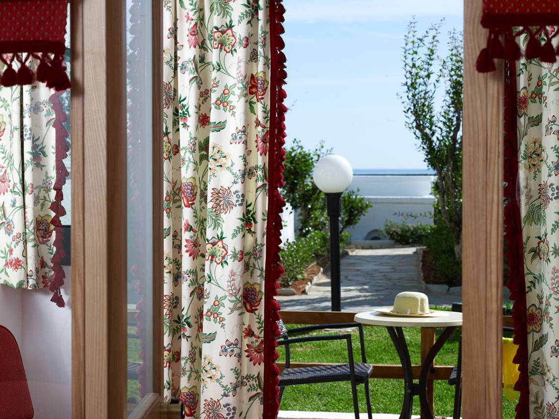 Aussicht aus dem Zimmer des Mitsis Rinela Beach Hotels mit Tisch, Hut und Garten