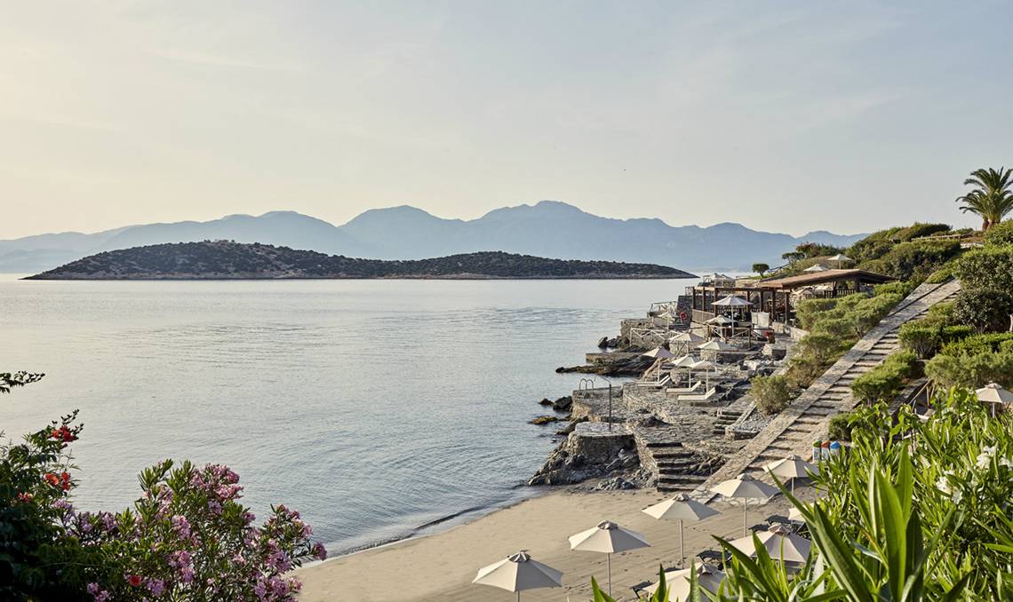Außenbereich des Minos Palace Hotel & Suites mit Blick auf das Meer und die Berge.