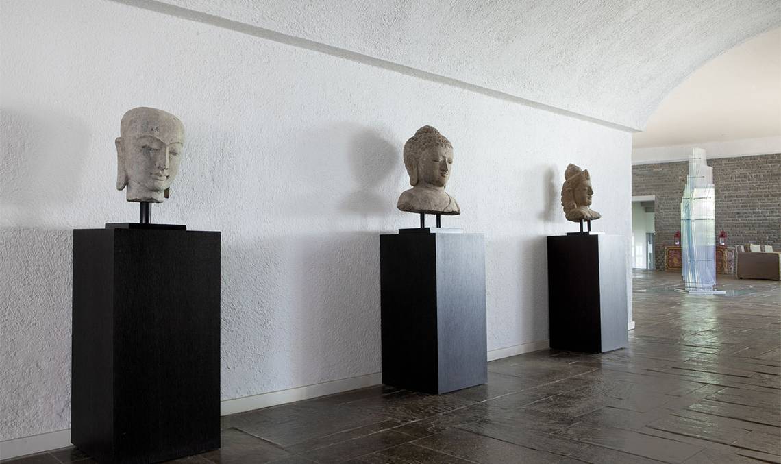 Drei Buddha-Kopf-Skulpturen auf schwarzen Sockeln im Minos Palace Hotel & Suites.