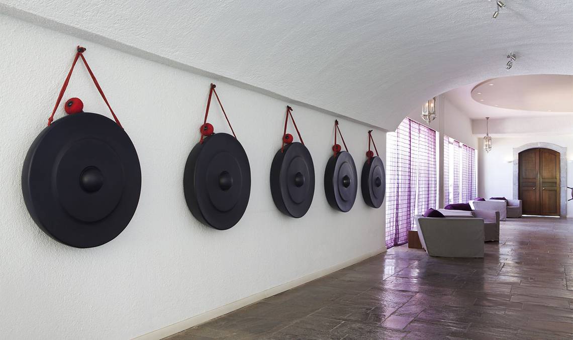 Ein Hotelkorridor mit schwarzen Gongs an der Wand und Möbeln in der Nähe.