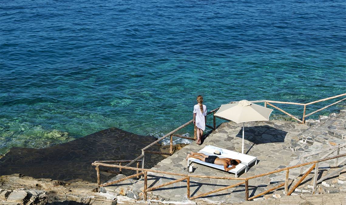 Personen auf der Terrasse des Minos Palace Hotel & Suites mit Blick auf das Meer.