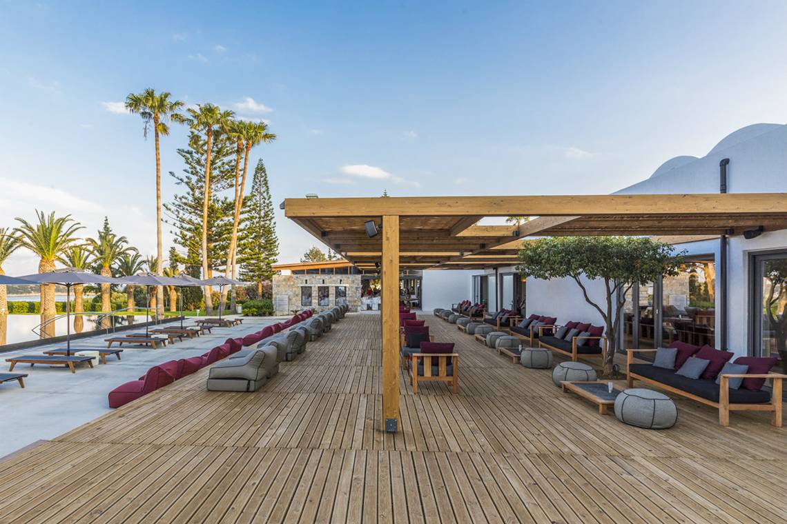 Lounge-Bereich des Minos Palace Hotel & Suites mit Holzdeck, Sitzgelegenheiten und Überdachungen