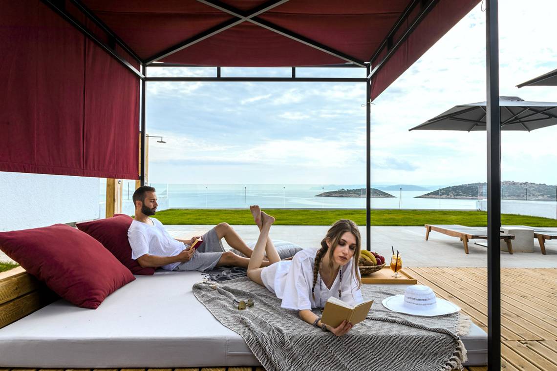 Paar auf Bett im Freien im Minos Palace Hotel & Suites mit Meerblick