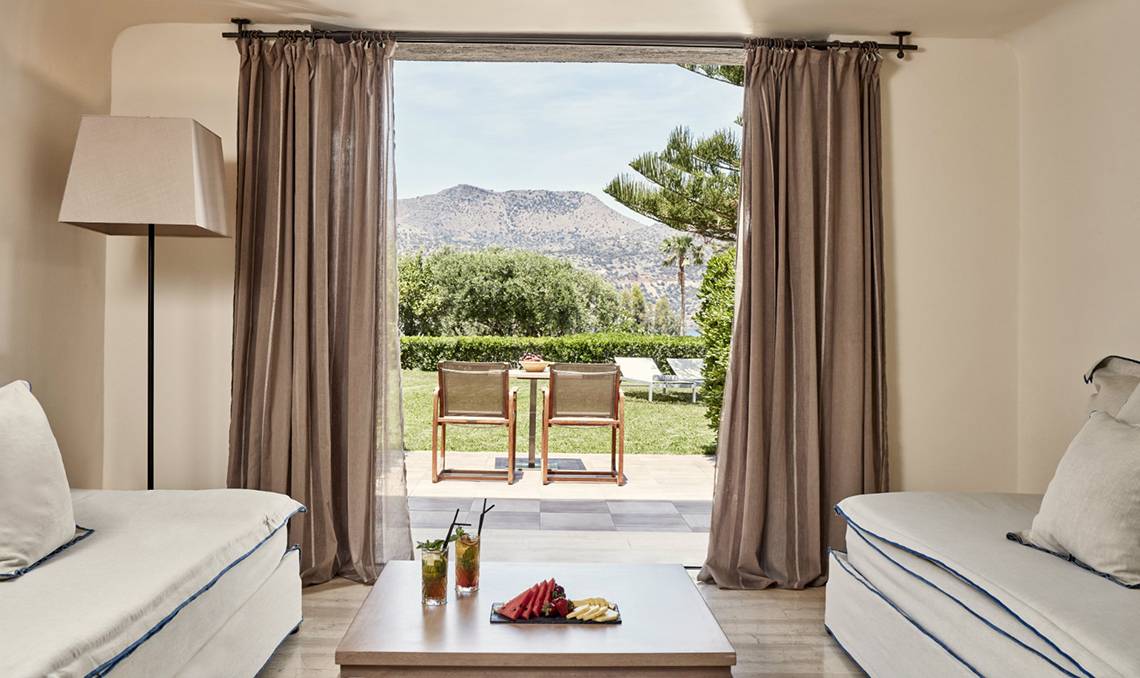 Innenraum der Minos Palace Hotel & Suites mit Blick auf eine Terrasse und Garten