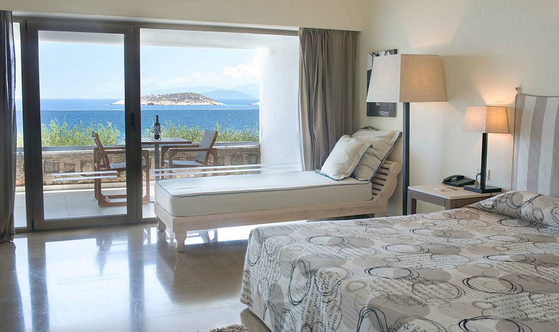 Minos Palace Hotel Suite mit Meerblick, Bett, Lounge-Bereich, Tisch und Telefon