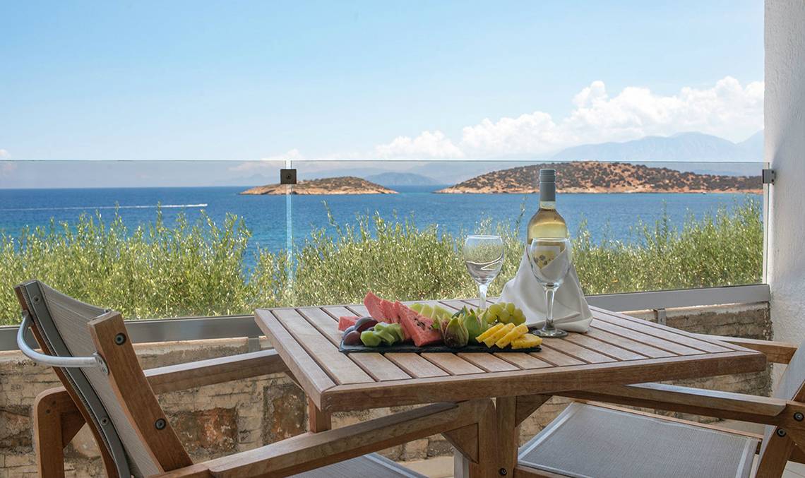 Balkon des Minos Palace Hotel & Suites mit Blick auf das Meer und eine Obstplatte.