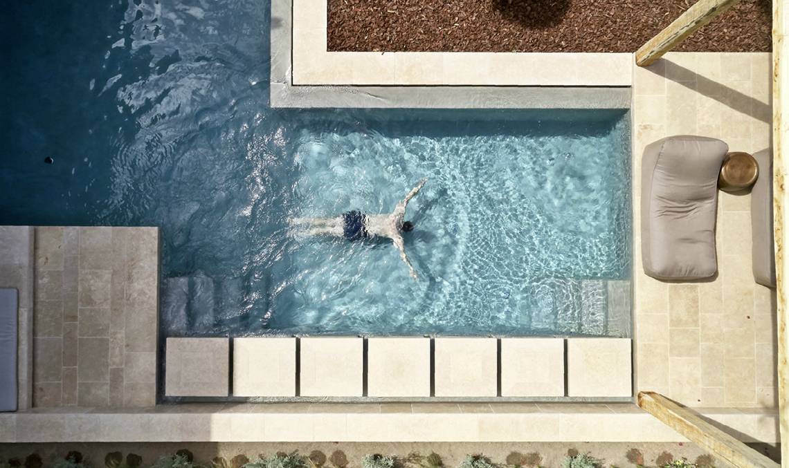 Luftaufnahme eines Schwimmers im Infinity-Pool im Minos Palace Hotel