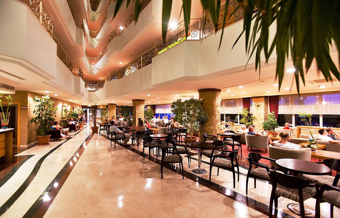 Lobby des Side Sun Hotels mit Gästen, Tischen, Stühlen und Pflanzen.