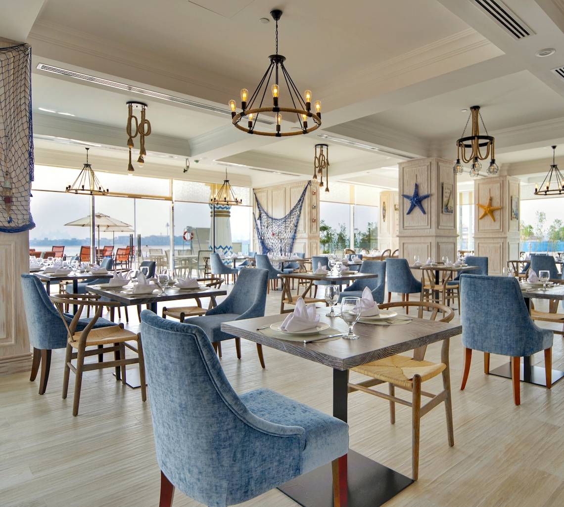 Restaurant im Royal Central Hotel The Palm mit blauen Stühlen und Tischen.