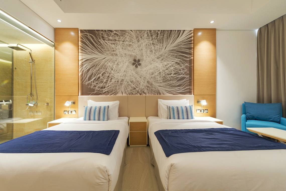Zwei Betten mit blauen Decken im Schlafzimmer des Royal Central Hotel The Palm