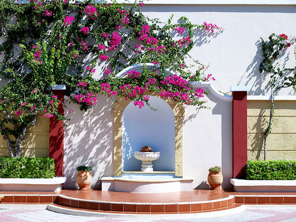 Eingang des Mitsis Summer Palace Beach Hotels mit blühenden Bougainvillea und Brunnen