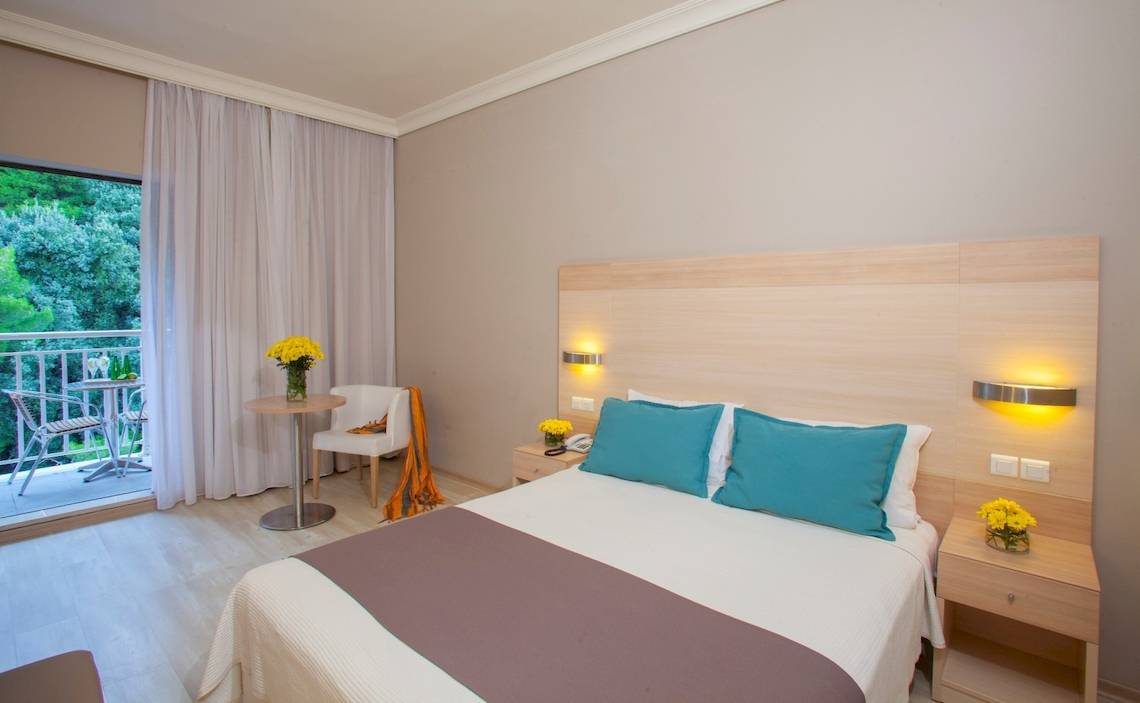 Hotelzimmer im Domes of Corfu, Autograph Collection mit Balkon, Tisch, Stühlen und Blumen.