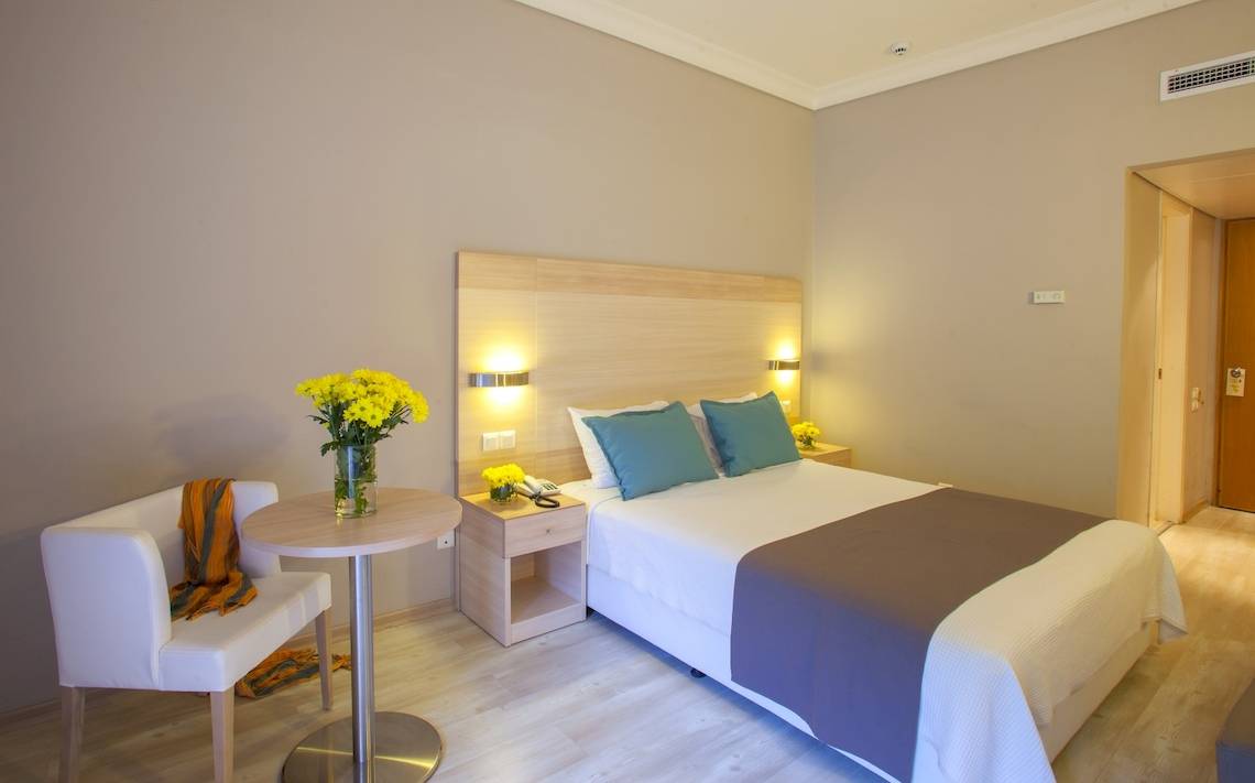 Hotelzimmer im Domes of Corfu, Autograph Collection mit Bett, Tisch und Blumenvase.