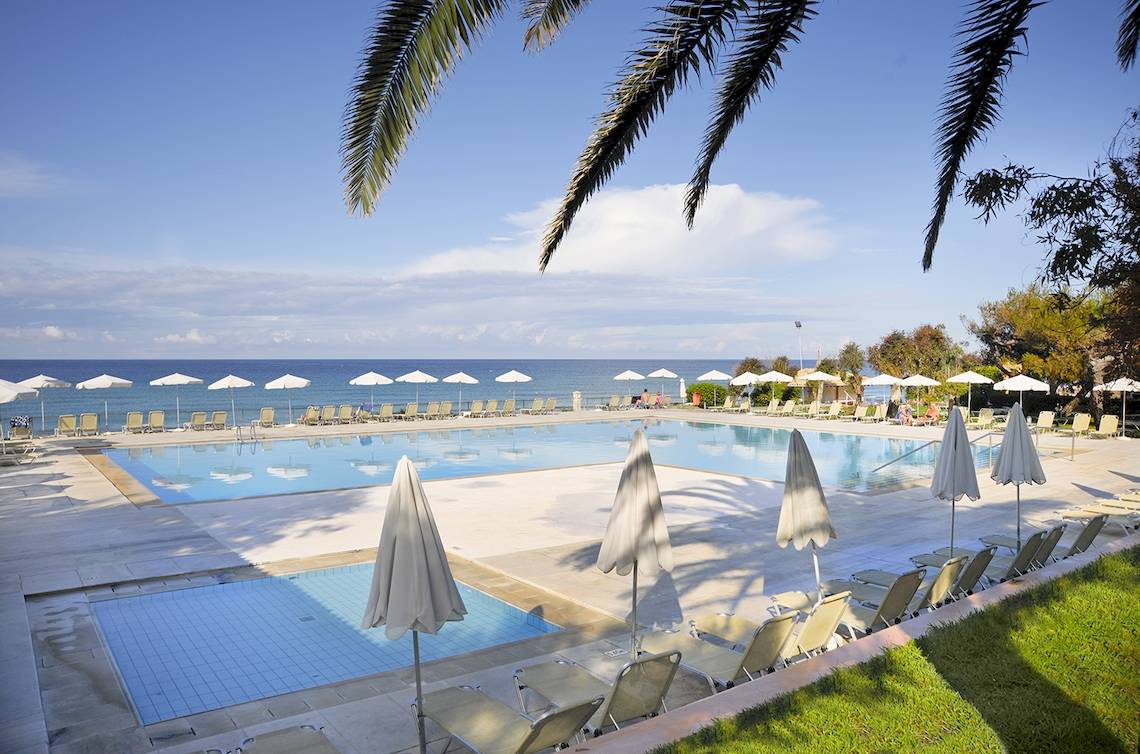 Strandhotel Schwimmbad mit Sonnenliegen und Sonnenhuten am Meer