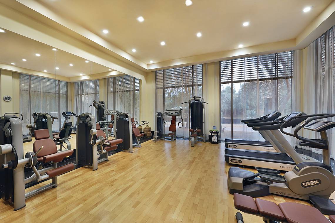 Fitnessstudio im Ritz-Carlton Ras Al Khaimah, Al Wadi Desert mit vielen Geräten und Holzboden