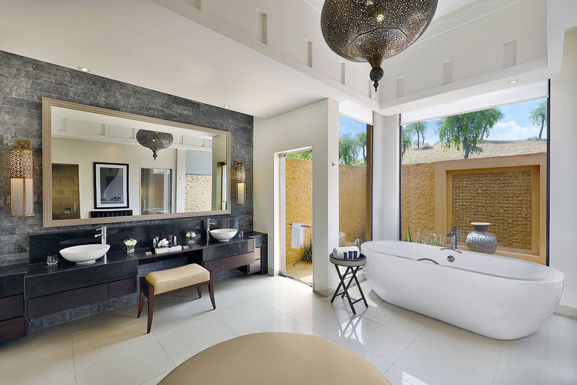 Das Badezimmer im Ritz-Carlton Ras Al Khaimah, Al Wadi Desert, mit zwei Waschbecken, einer Badewanne und einer Dusche.