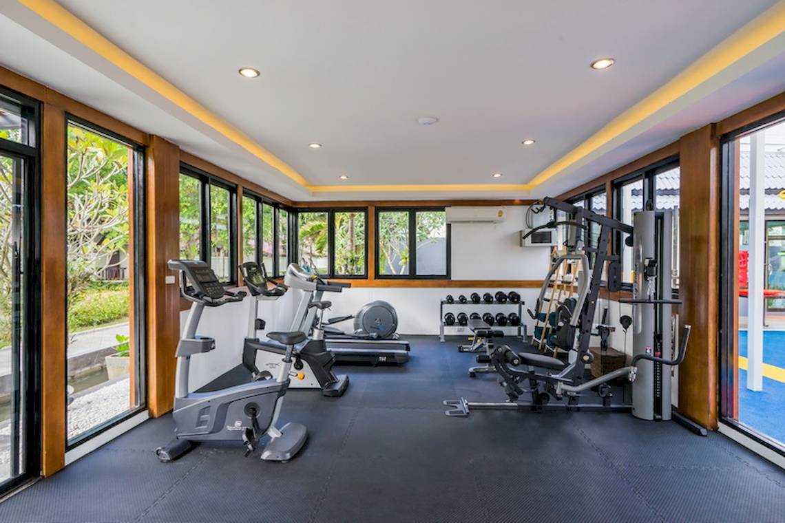 Fitnessbereich im Khao Lak Emerald Beach Resort & Spa mit Geräten und Fenstern.