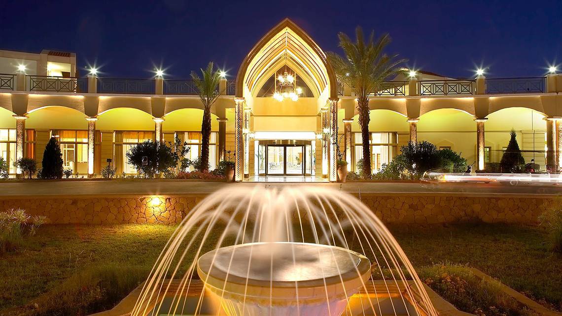 Die beleuchtete Fassade des Lindos Princess Beach Hotels mit einem Brunnen vor dem Eingang.